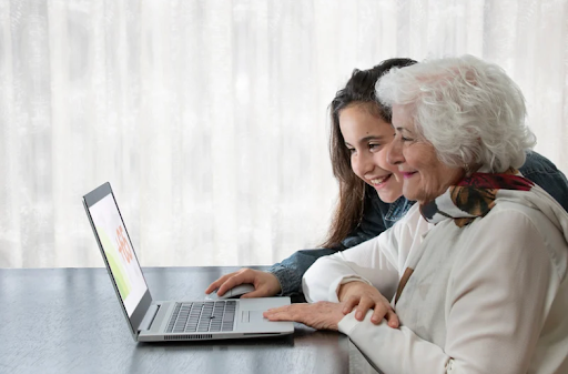 Eine junge und eine ältere Frau lächeln beim Blick auf einen Laptop, was die Bedeutung von Bildung bei COPD zeigt.