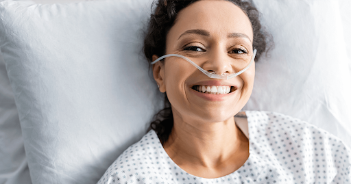 Smiling woman in a hospital bed receiving oxygen therapy for COPD.