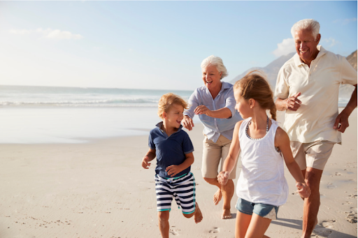 Großeltern mit ihren Enkeln, die am Strand rennen, und die Bedeutung der Familie für die Lebensqualität von COPD-Patienten zeigen.