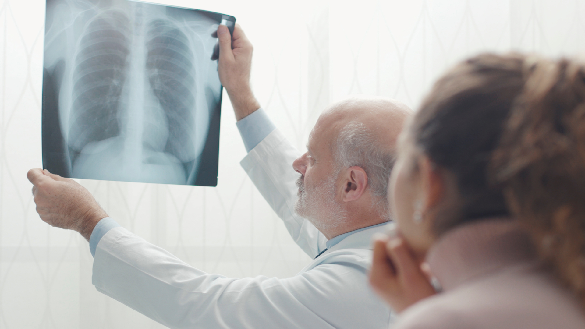 Doctor explaining a CT scan result to an adult during a lung screening consultation.