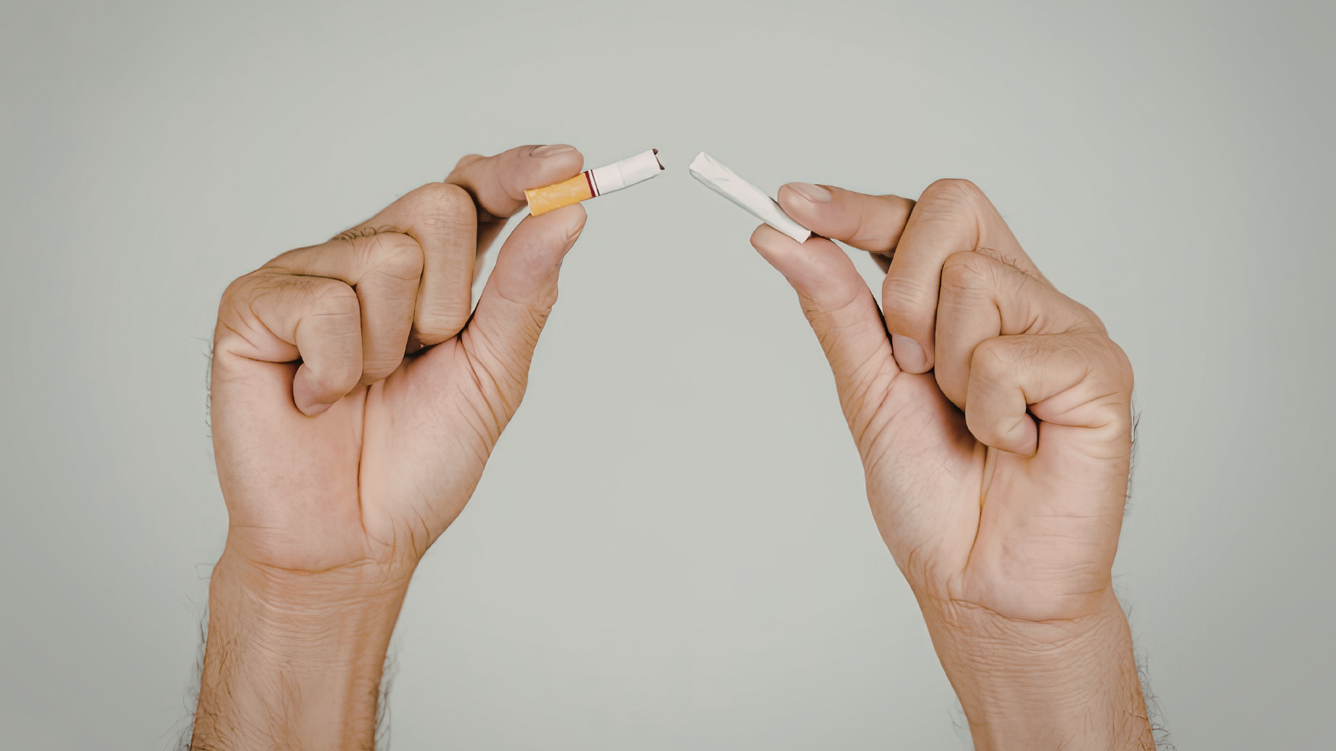 Person holding a cigarette while thinking about quitting smoking and making healthier lifestyle changes.
