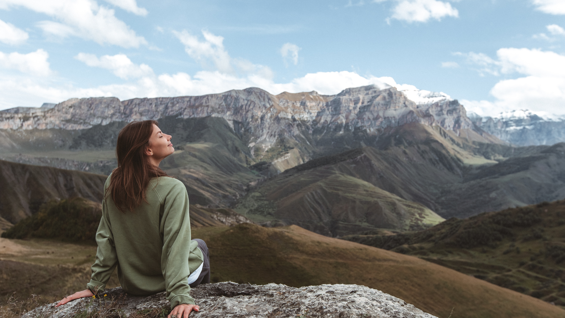Woman sitting outdoors in the mountains and breathing fresh air.