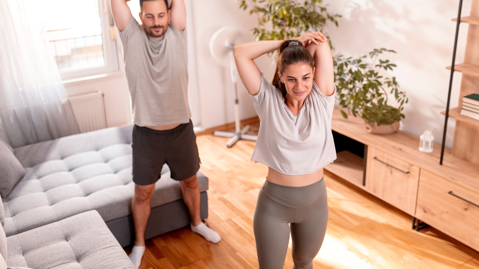 A couple doing light stretches in a tidy living room to reduce asthma triggers.
